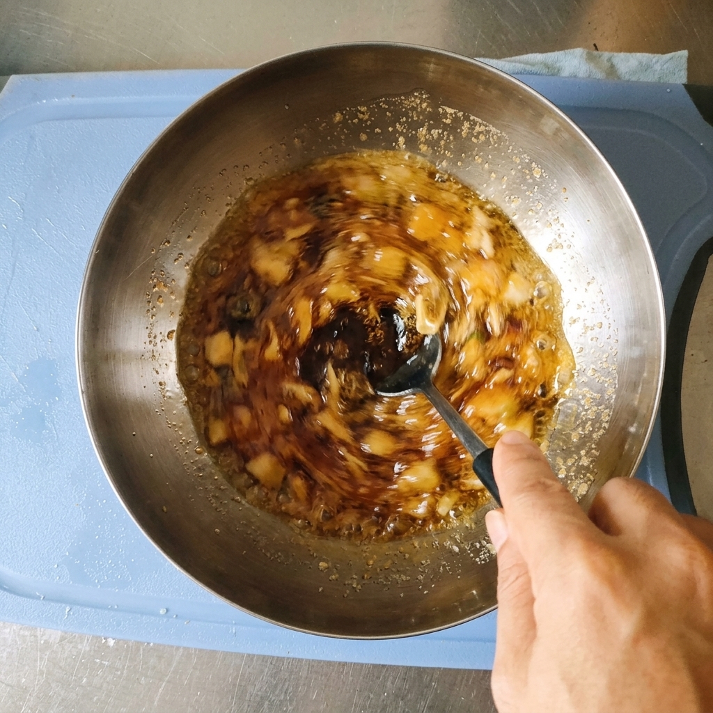 A hand stirring a dark brown marinade containing minced garlic and green onions in a stainless steel bowl with a spoon.
