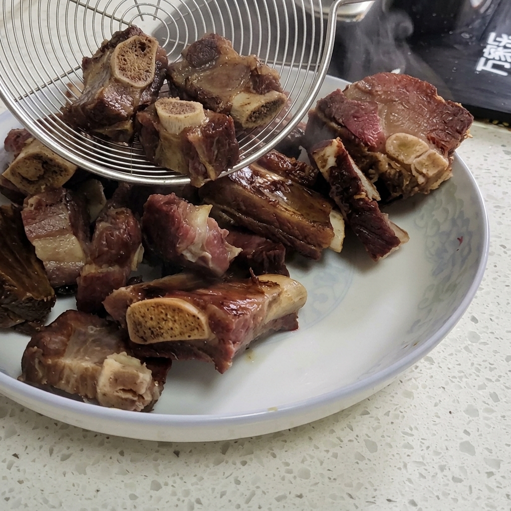 A metal spider strainer lifting boiled cured pork ribs out of a steaming wok onto a plate.