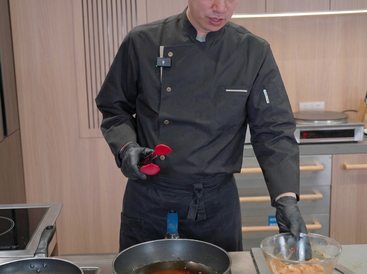 Marinated squid pieces cooking inside a large pan filled with hot, bubbling oil as the chef prepares to manage the frying process.