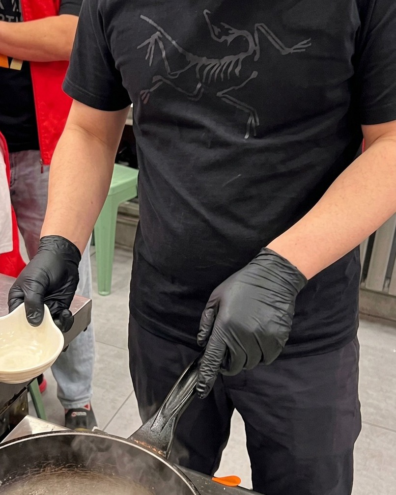 Scored squid pieces being blanched briefly in a pot of boiling water with steam rising.
