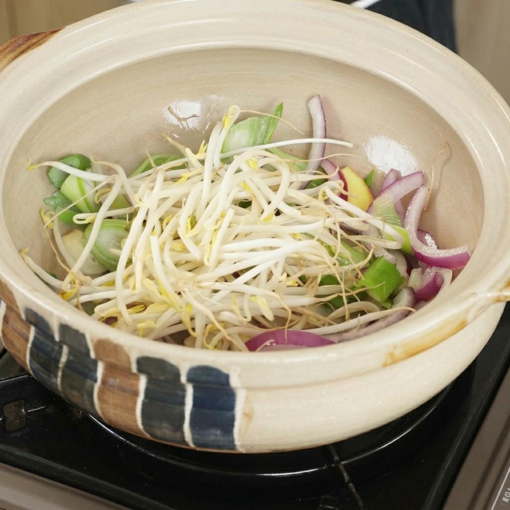 A generous handful of white bean sprouts layered over onions and green scallions inside a clay cooking pot.
