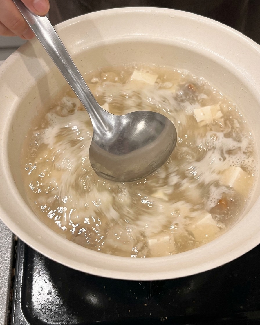 Water and sake being poured into a clean pot from a measuring cup.