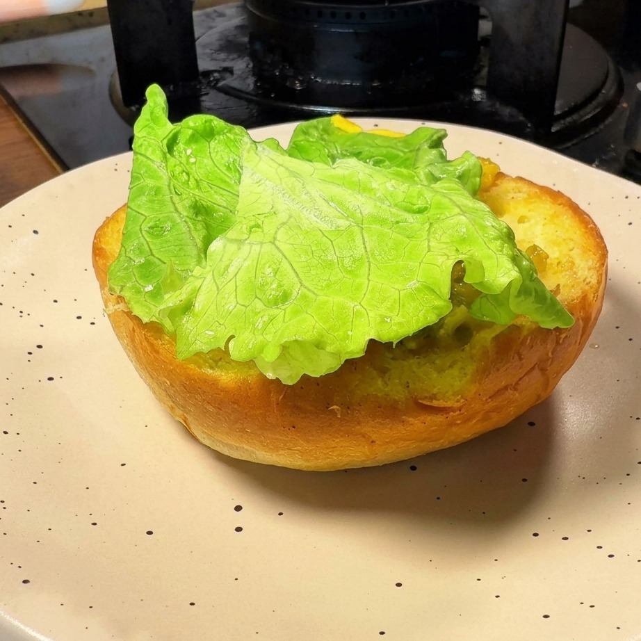 A toasted burger bun base topped with a fresh green lettuce leaf.