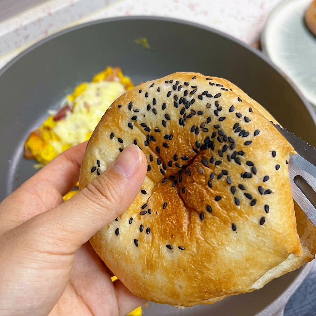 A toasted burger bun with black sesame seeds being sliced open.