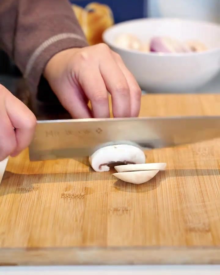 Finely chopped mushrooms, bacon strips, and diced red onions arranged neatly on a wooden cutting board.