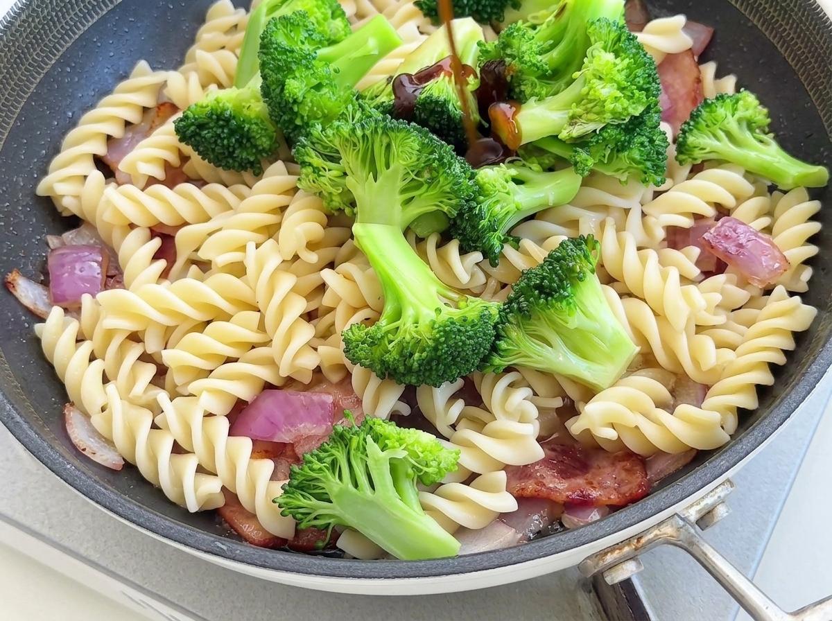 Mushroom sauce, oyster sauce, and black truffle sauce being measured out and added to the pasta and broccoli in the pan.