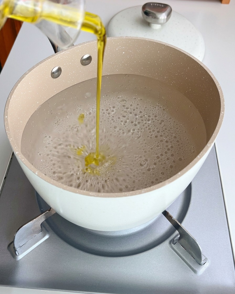 Spaghetti noodles boiling in a pot of water with oil.