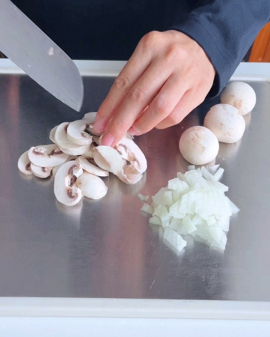 Bacon strips being diced on a metal cutting board.
