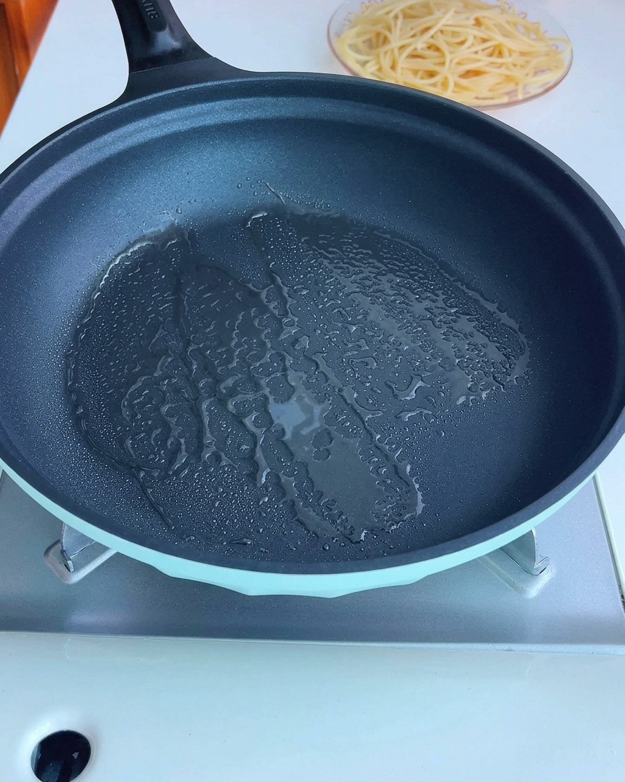 Diced bacon frying in a pan with olive oil.