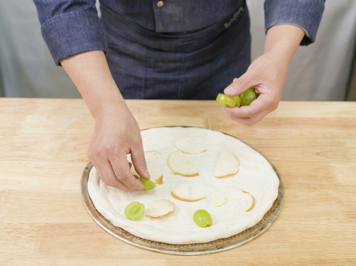 Fresh halved tomatoes being placed onto the pizza base.