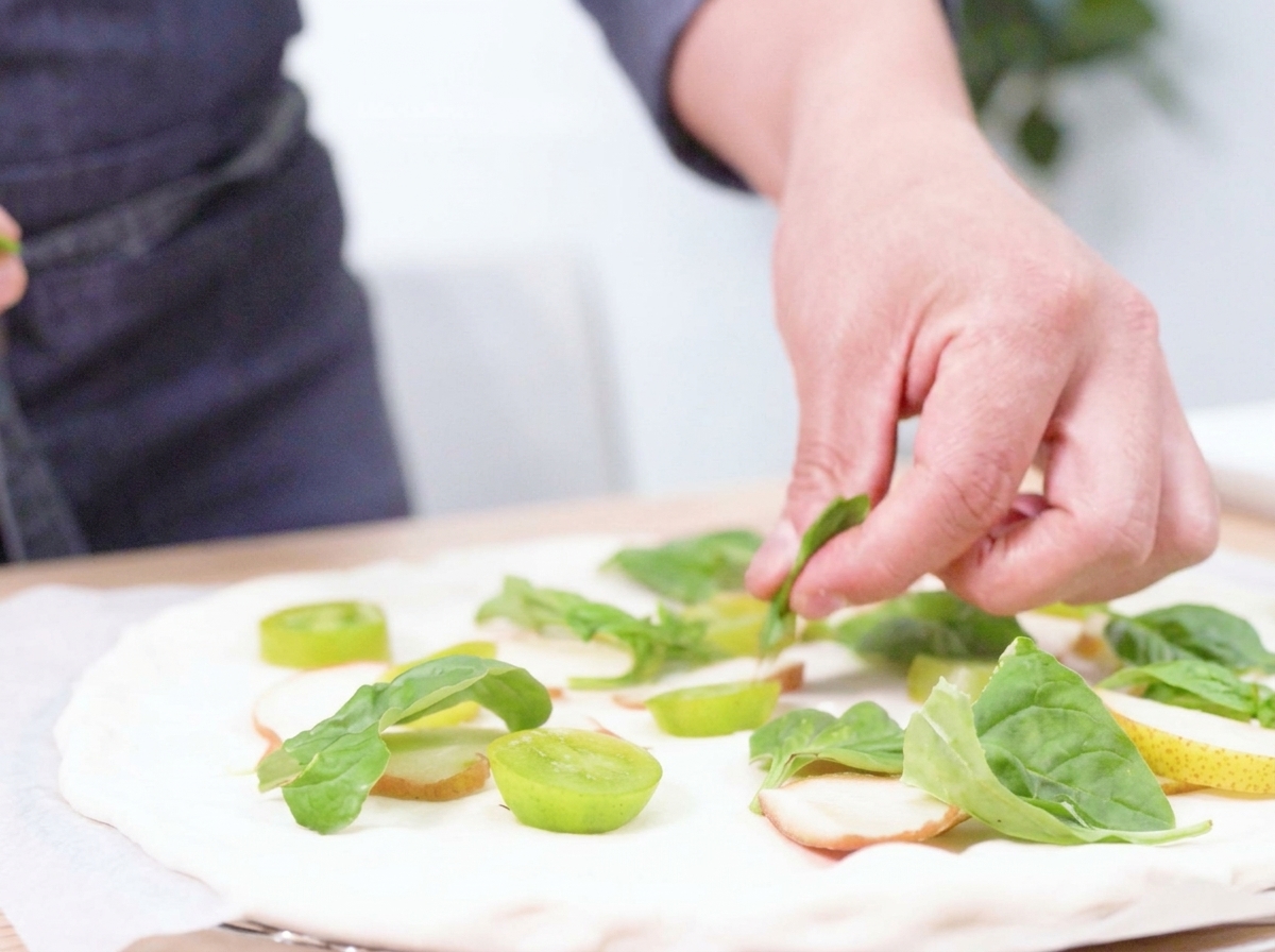 Hand-tearing fresh buffalo mozzarella onto the prepared pizza.