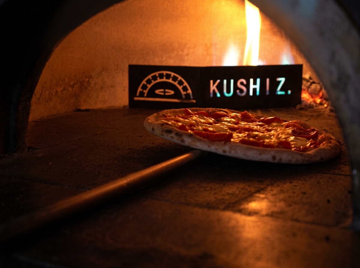 A pizza baking in a wood-fired oven with visible flames in the background.