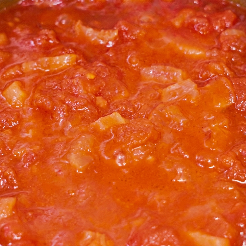 A close-up view of the tomato and bacon sauce simmering in the pan.