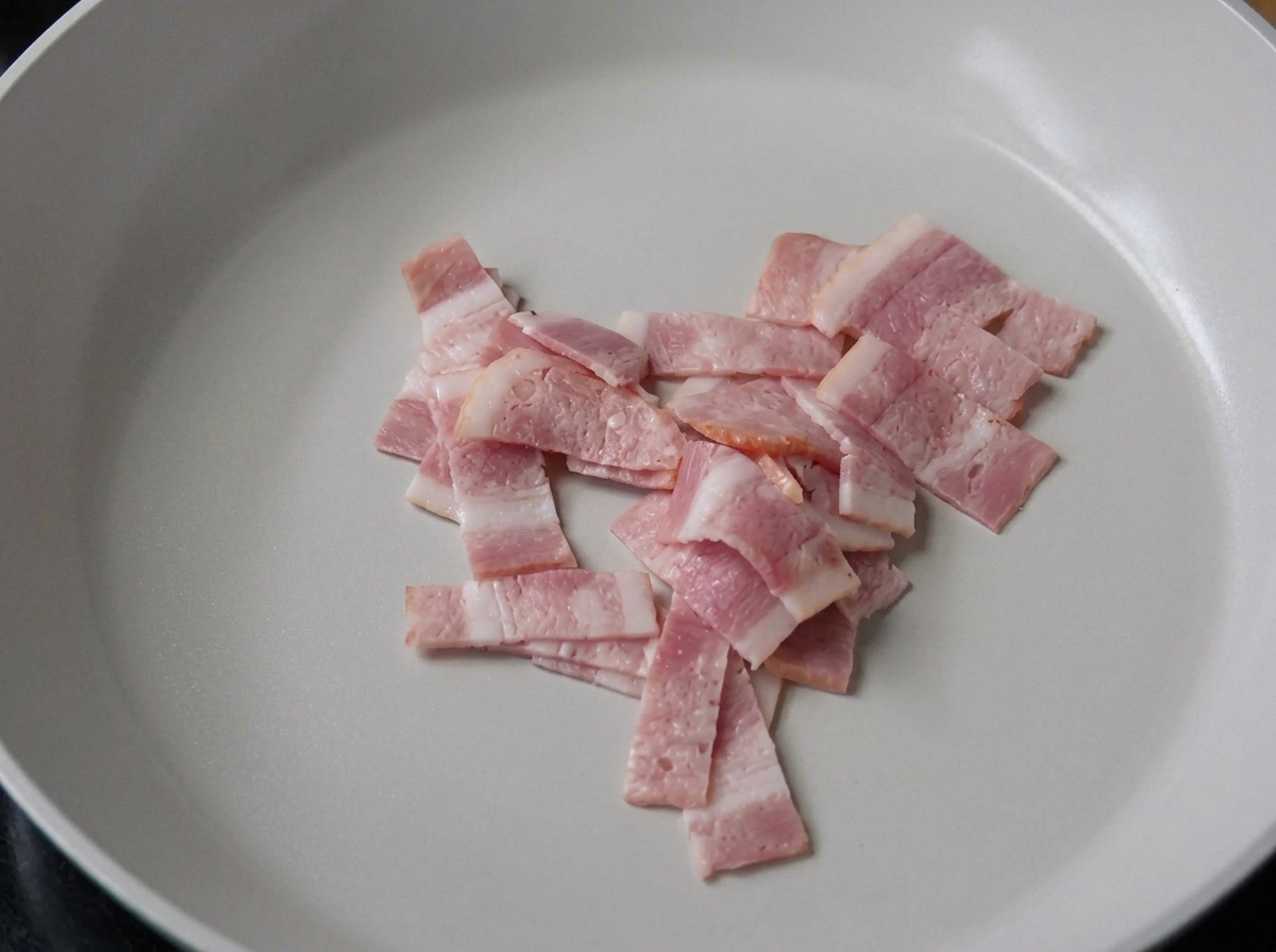 Bacon slices sizzling in a pan.
