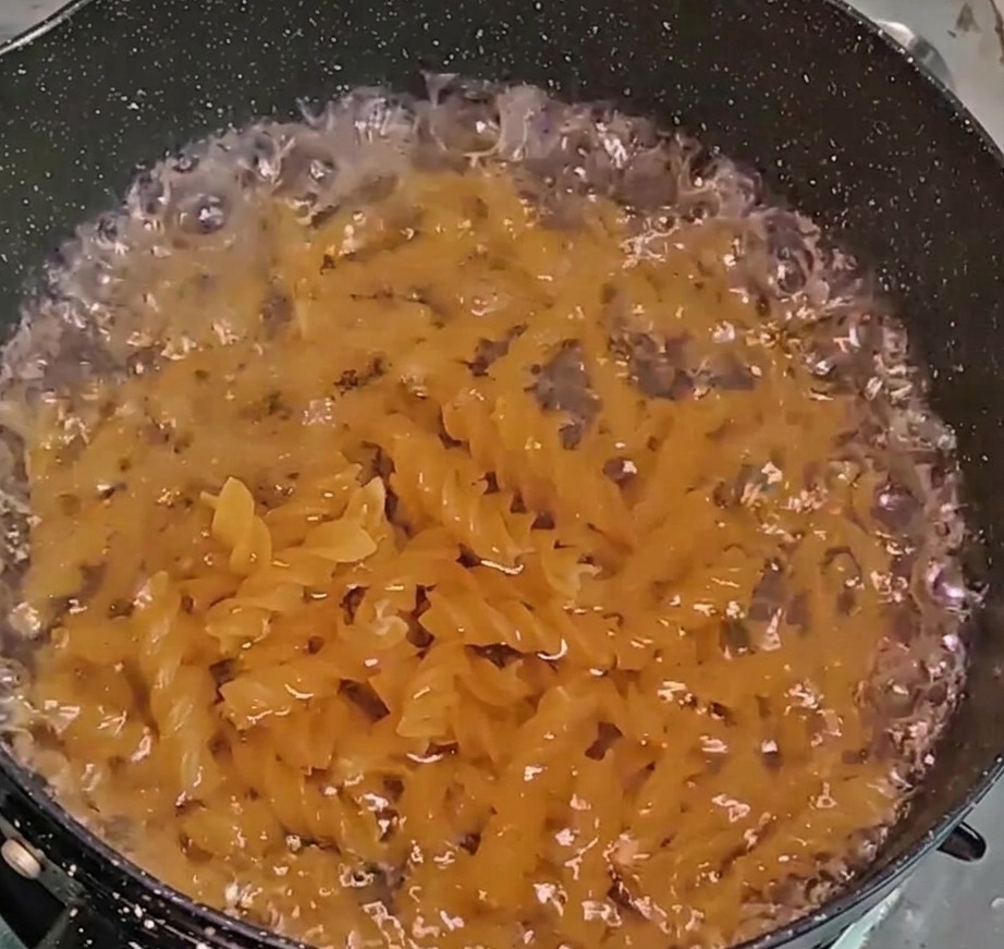 Fusilli pasta cooking in a pot of bubbling water.