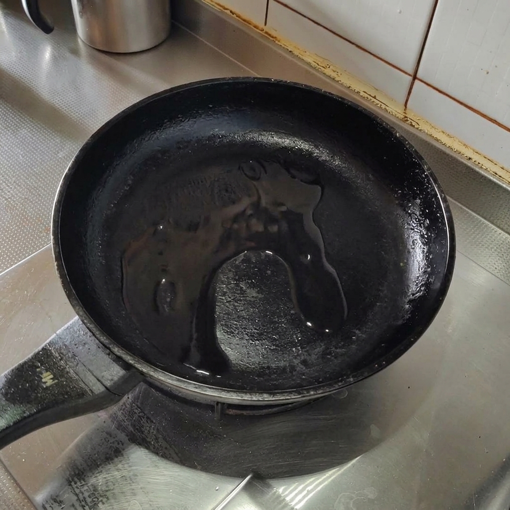 Crispy bacon pieces frying in olive oil in a stainless steel pan.