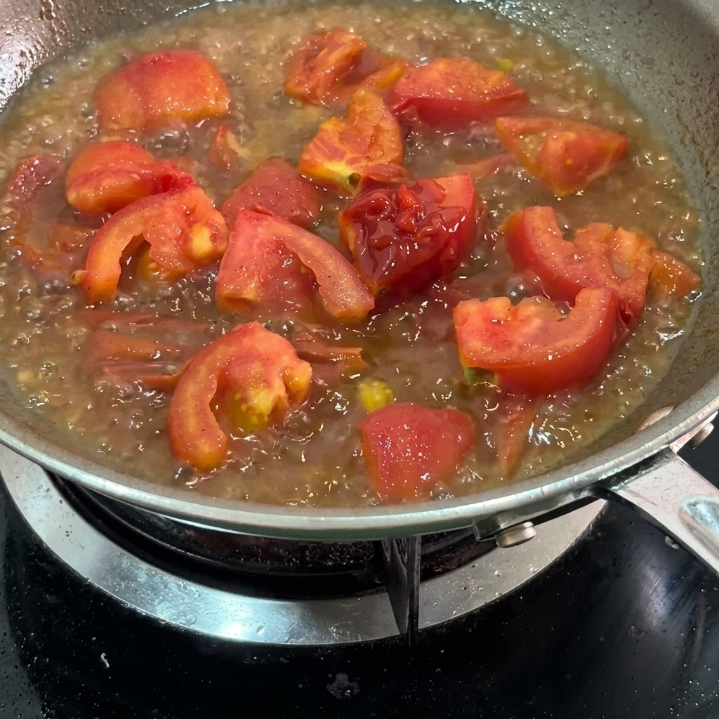 Ketchup being swirled into the simmering tomato mixture.