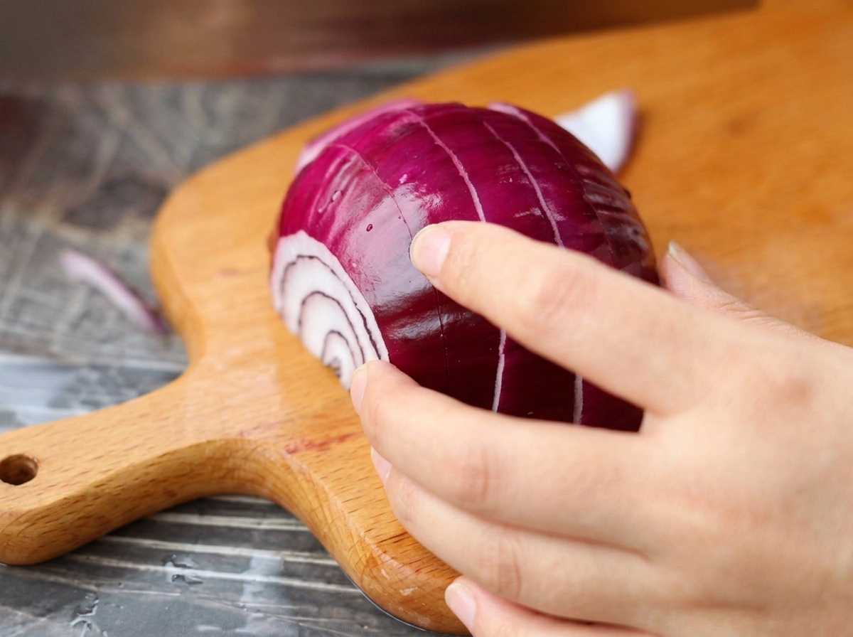 A red onion being diced into small pieces on a wooden board.