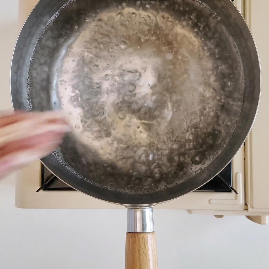 Thin slices of fatty beef being blanched in a pot of boiling water.