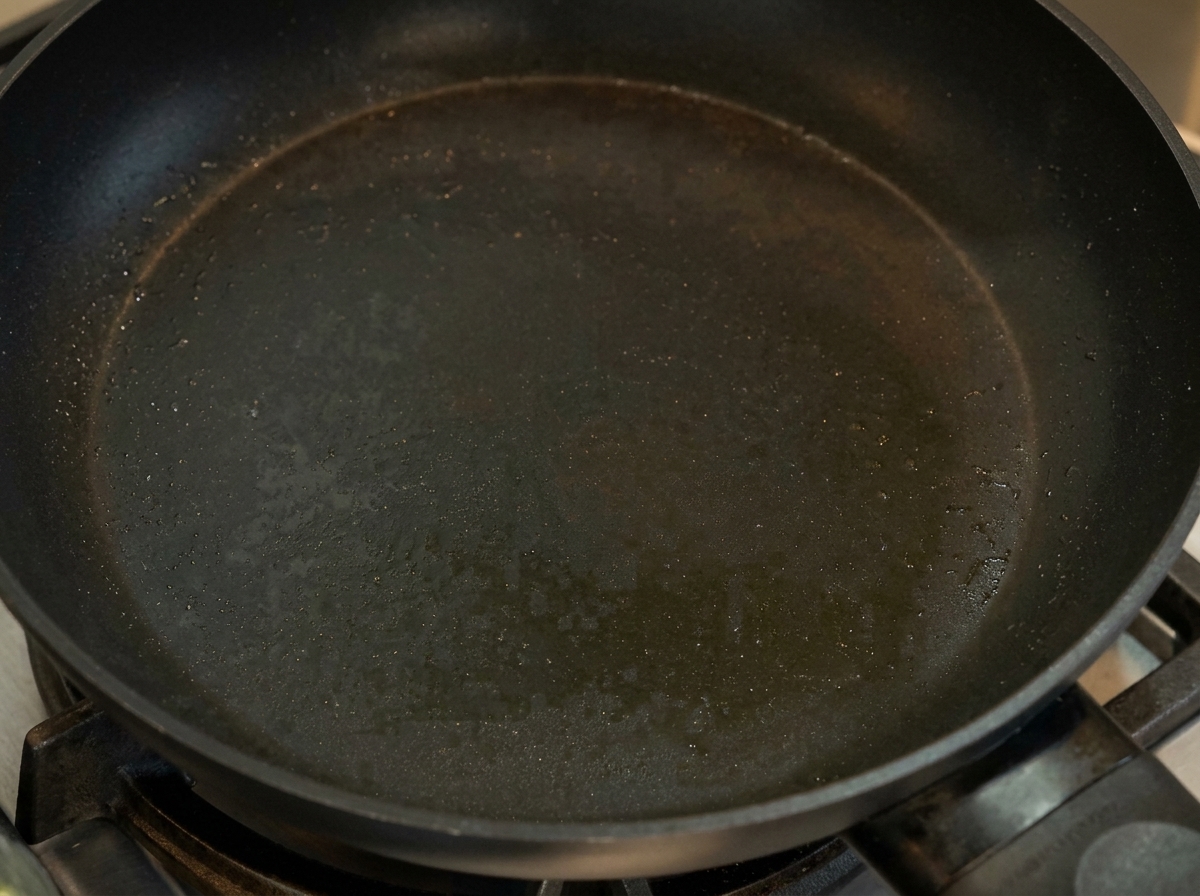 A thin, cooked yellow egg pancake being folded in a non-stick pan.