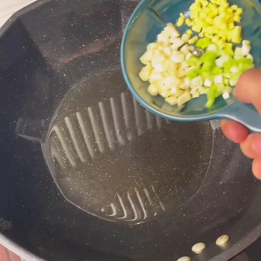 Chopped green onions and garlic sizzling in hot oil in a wok.