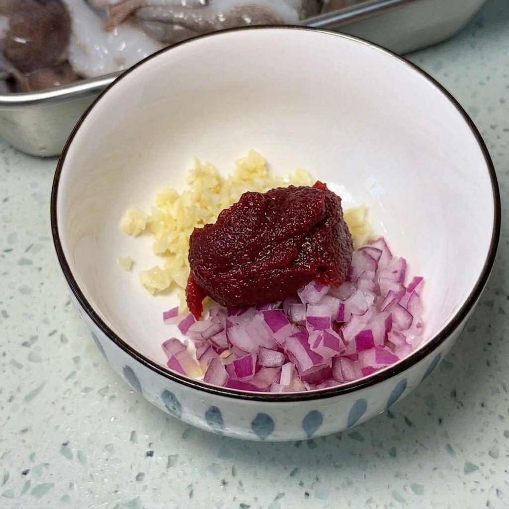 A wide metal pan arranged with sliced spam, sausages, and cubes of tofu, ready to be cooked.