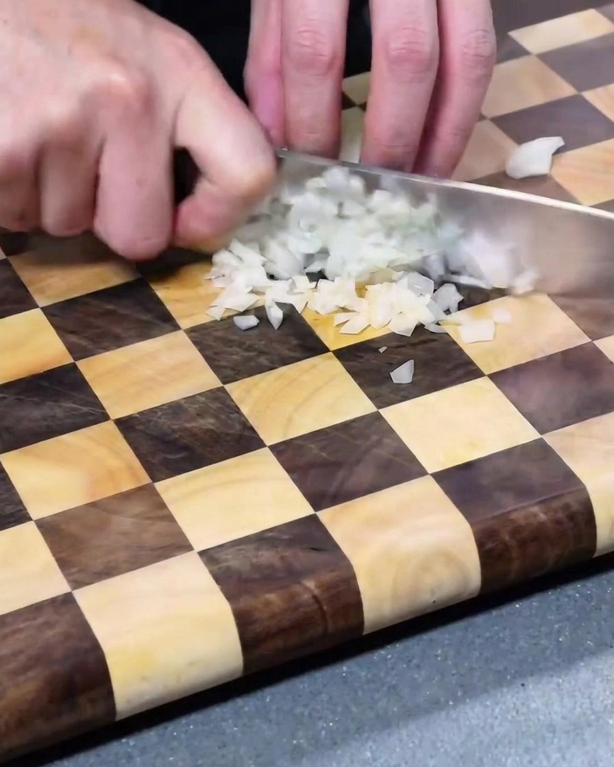 Finely diced white onion pieces scattered on a wooden cutting board.