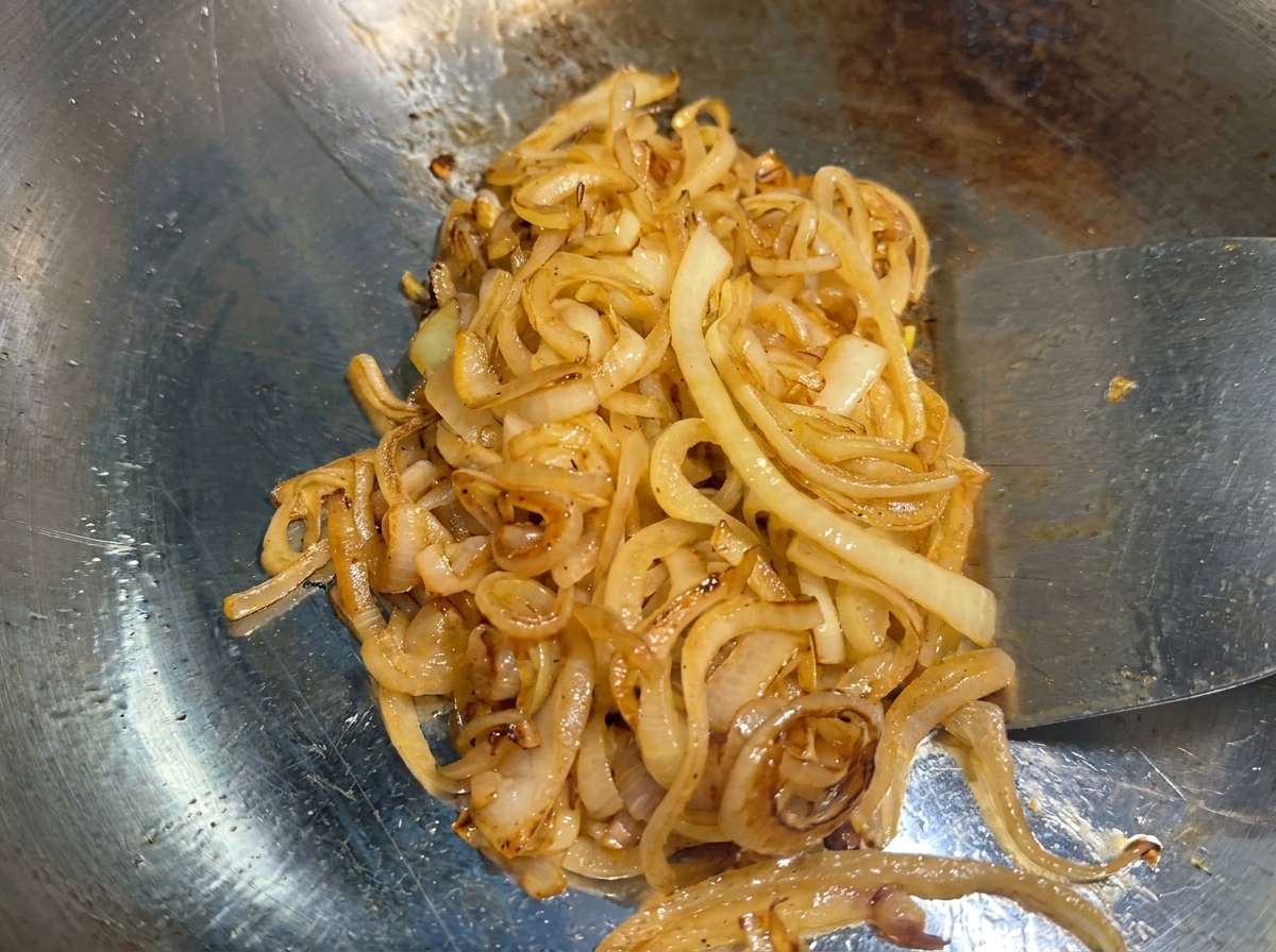 Onions on the grill cooked down to a deep, golden-brown caramelized state.