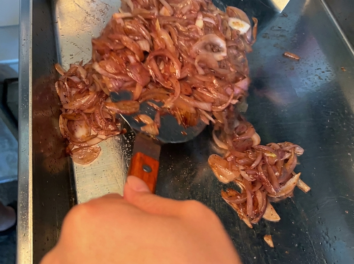 Dark soy sauce marinade being poured over raw pork belly pieces in a metal bowl.