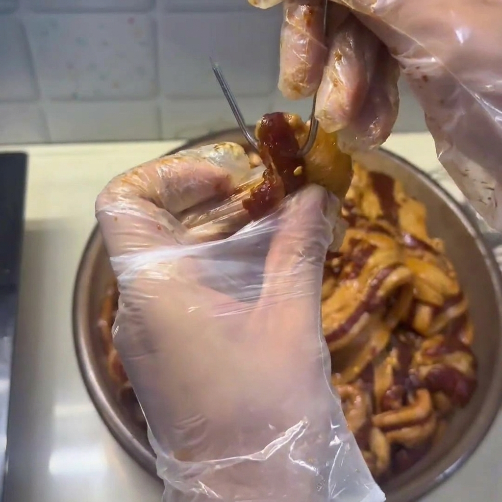 Firm, air-dried pork belly strips being carefully arranged in a steamer basket.