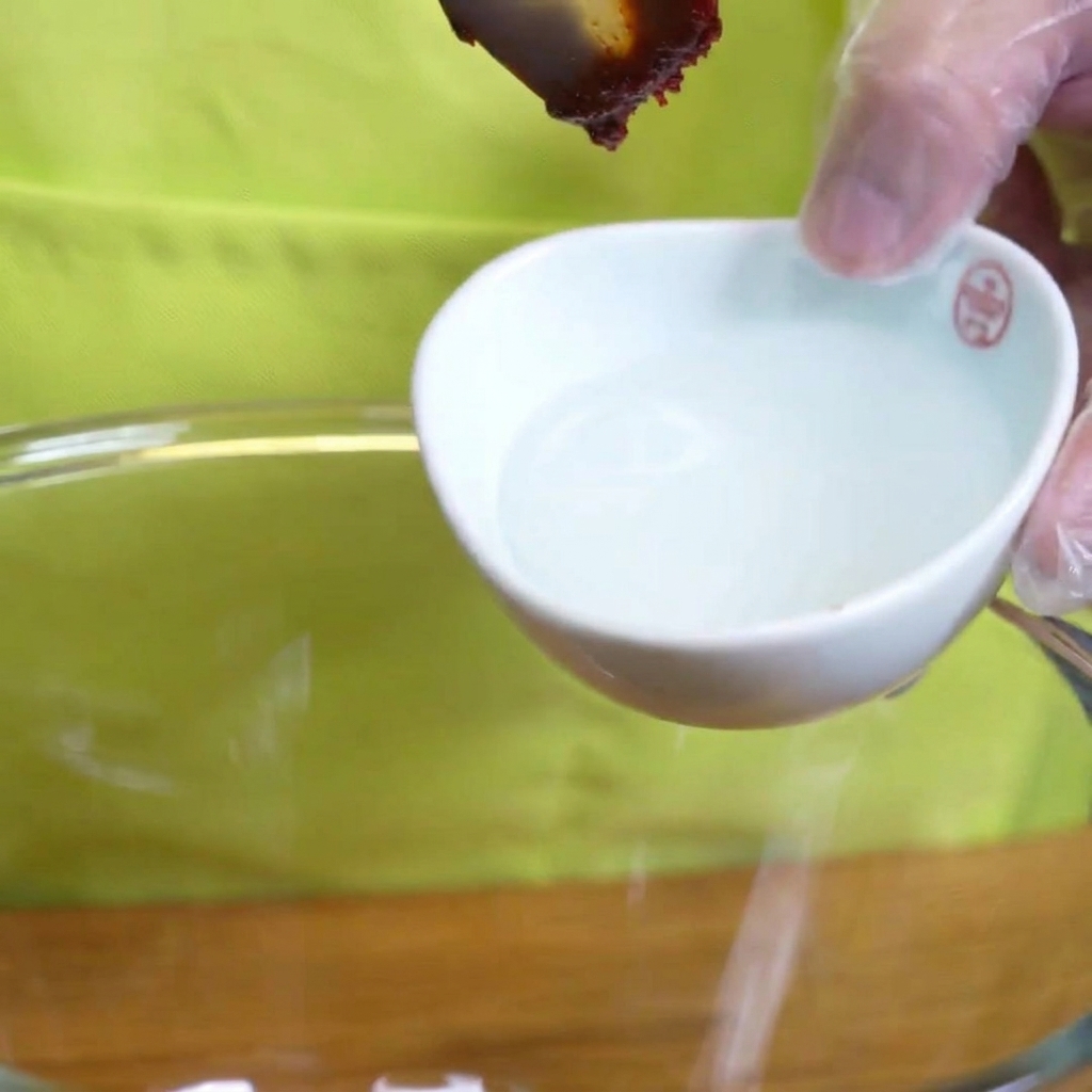 Thick starch syrup being drizzled from a spoon into a bowl with marinade ingredients.