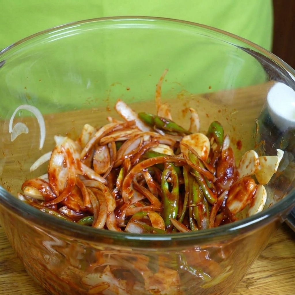 Raw, thinly sliced pork belly strips being added to a bowl of marinade and sliced vegetables.
