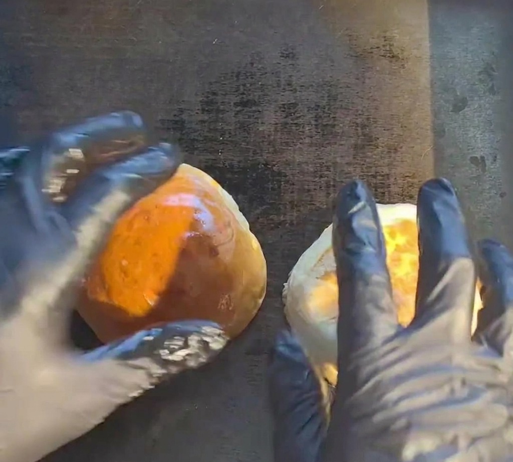 A raw beef patty sizzling on a hot flat-top grill.