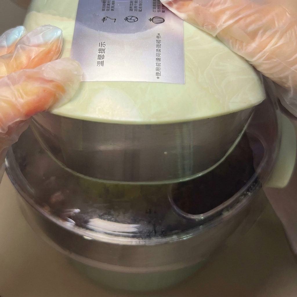 Hands shaping a portion of dough into a smooth, round ball.