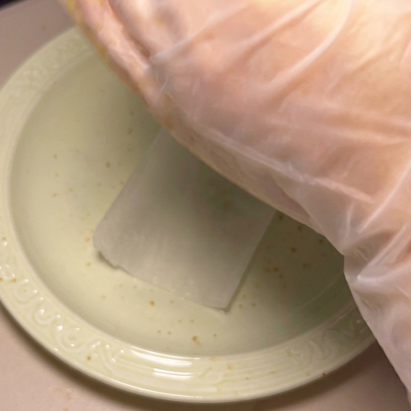 A hand shaping a portion of seasoned raw ground beef into a uniform, round patty.