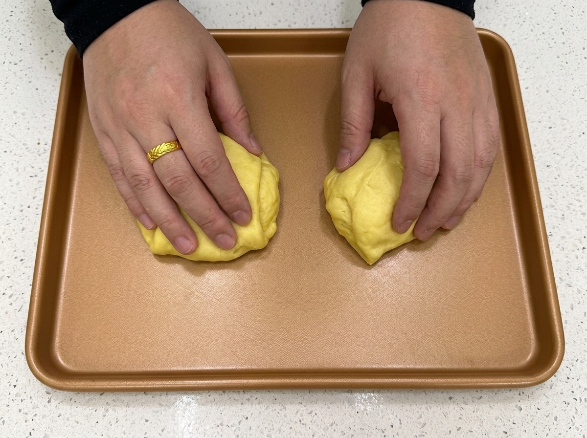Dough pieces being cut into equal portions using a bench scraper on a flat surface.