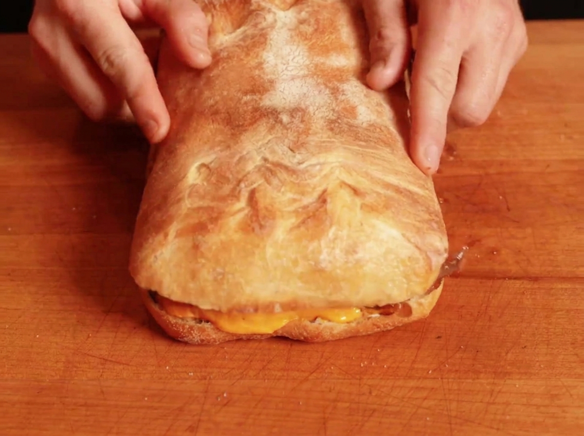 The top piece of bread being placed over the filled sandwich base to complete the assembly.