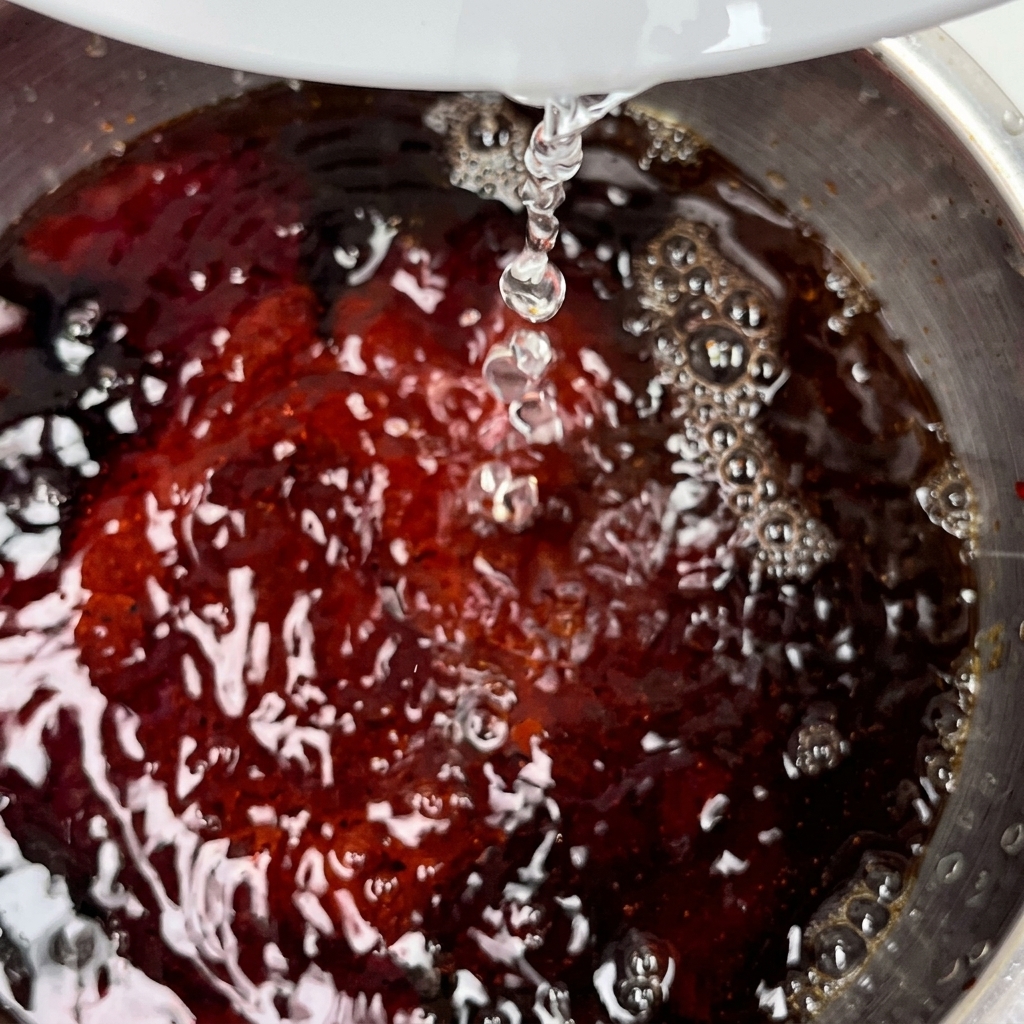 A knob of butter melting in a hot stainless steel pan.