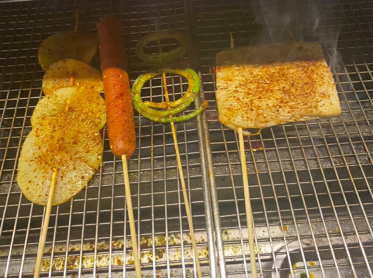 Grilled potato slices, sausage, and vegetables coated in a glossy barbecue sauce and chili flakes.