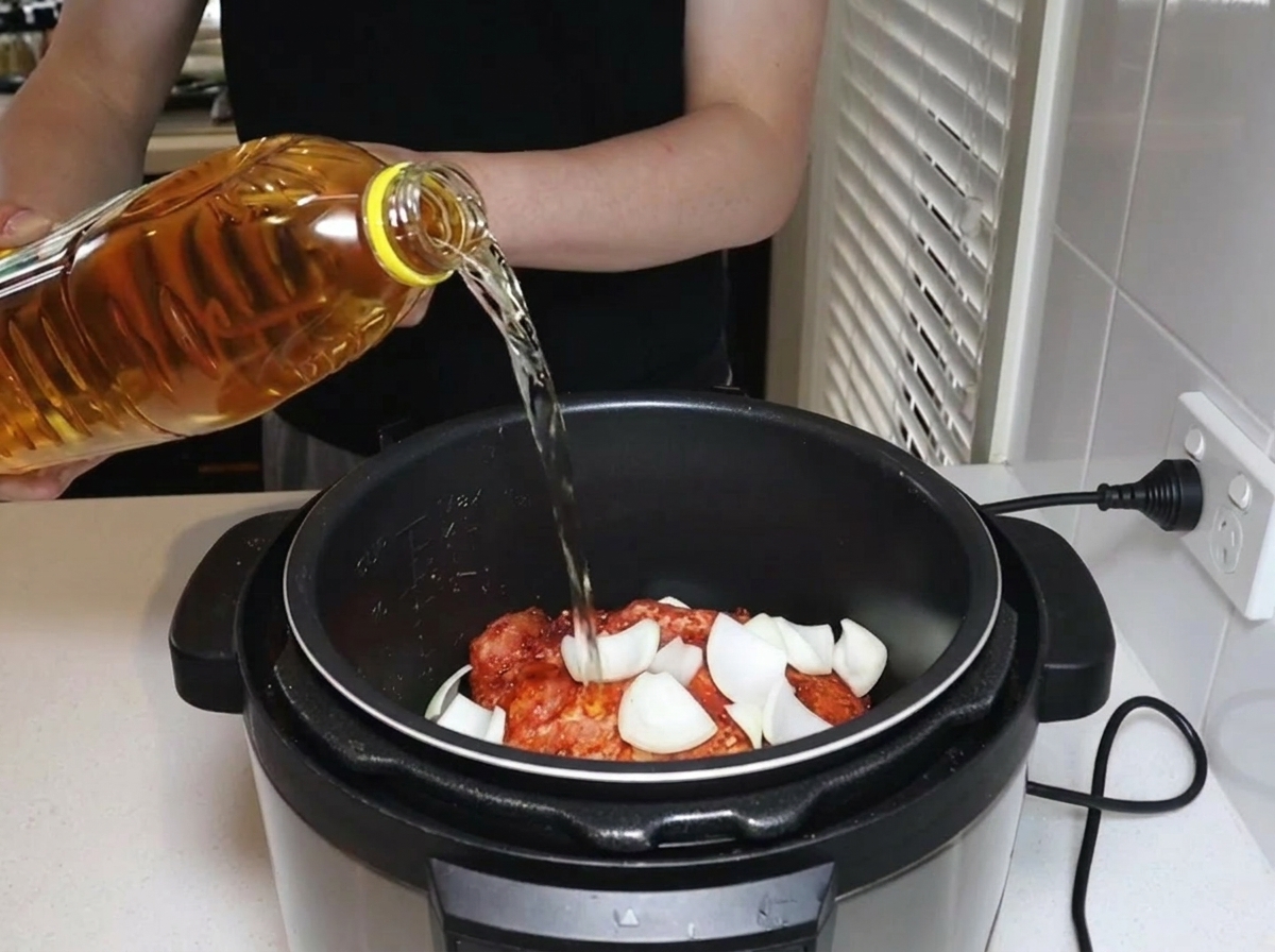 Apple juice being poured from a plastic bottle into the pressure cooker.