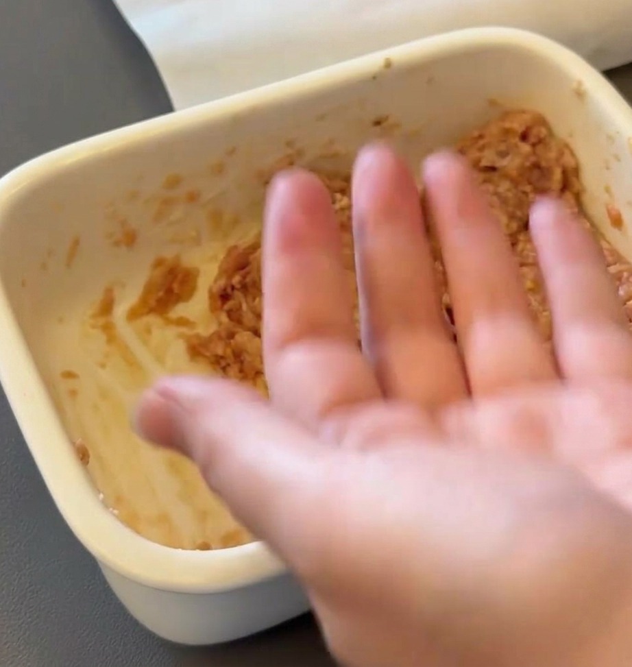 A hand shaping raw ground beef mixture into a round patty.