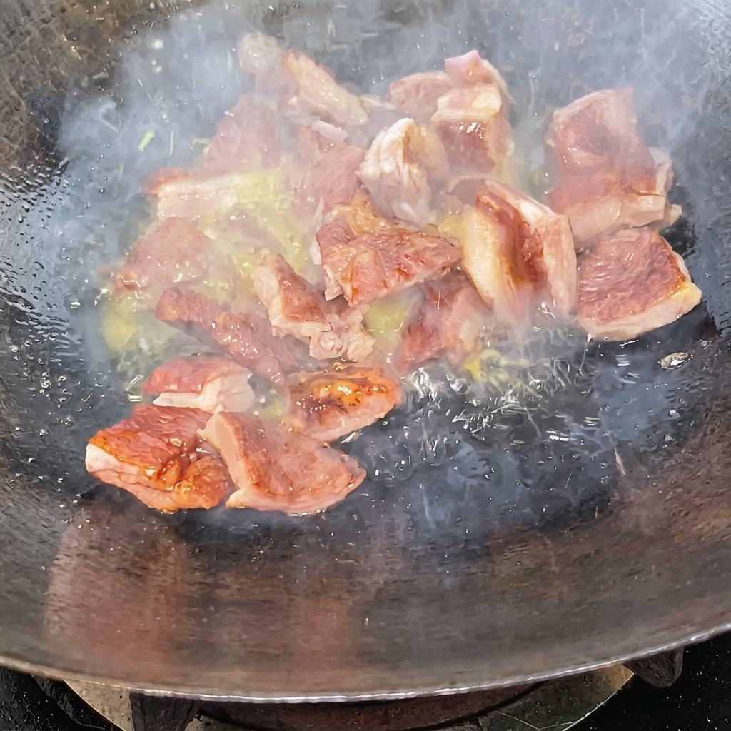 Rib pieces being stir-fried in a wok coated in a dark caramel glaze.