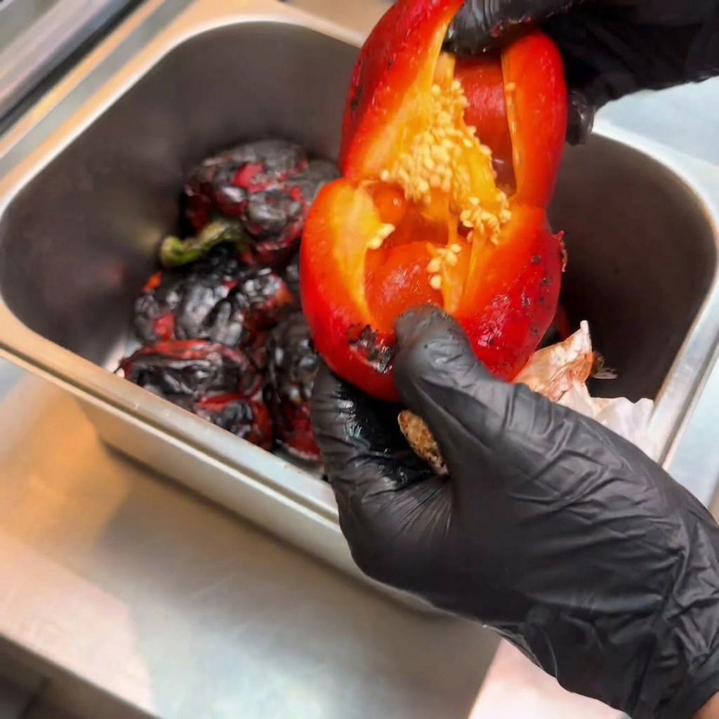 Peeled roasted bell pepper opened up to reveal the interior with seeds being removed.