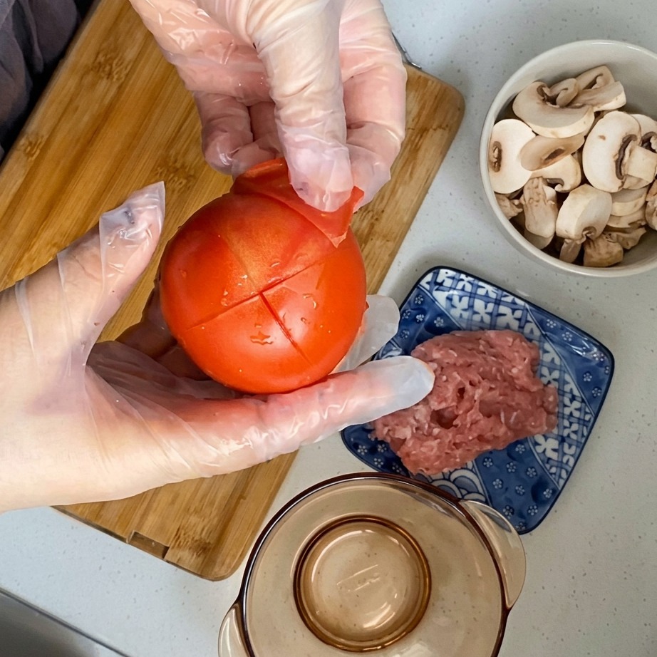 The skin being peeled off a blanched, scored tomato.