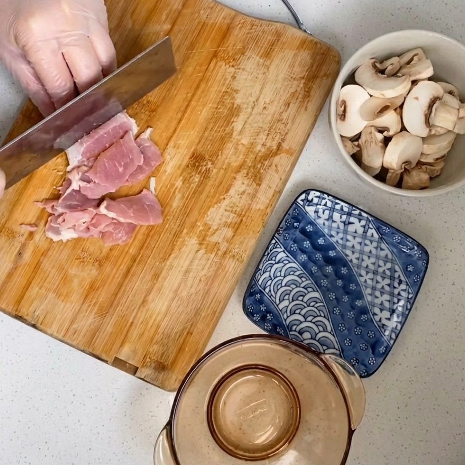 Raw pork meat being chopped into a fine mince on a wooden board.