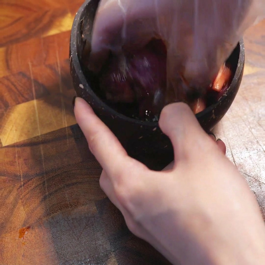 A gloved hand mixing raw sliced beef with dark seasonings in a bowl.