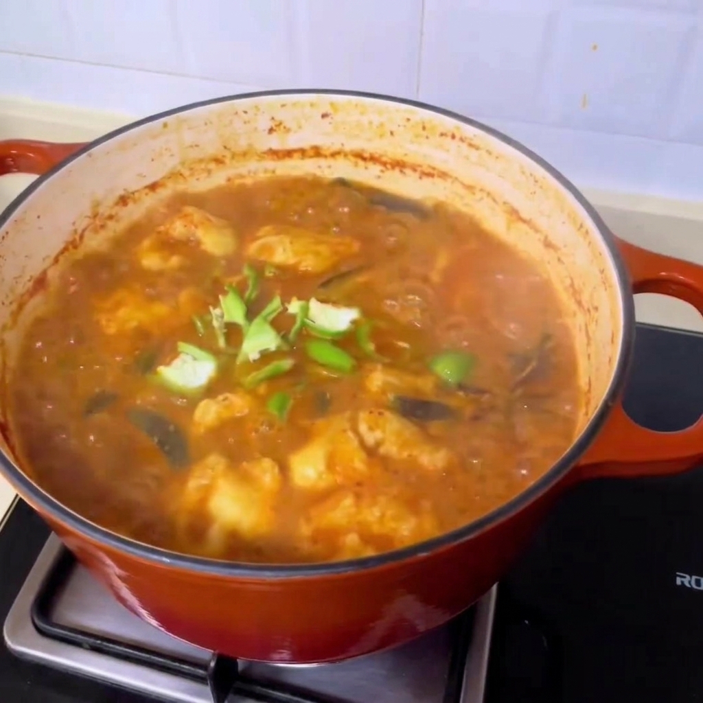 Fresh green chili slices being scattered over the bubbling, rich Korean-style clam soup.