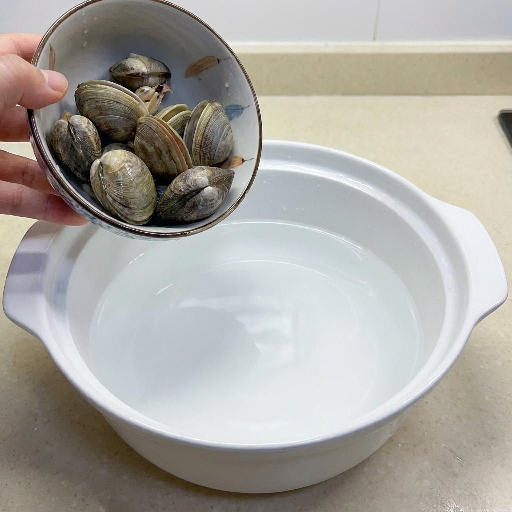 A bowl containing several raw clams ready for cooking.