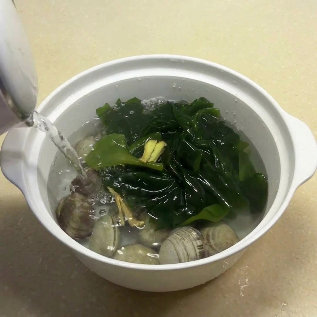 Hot water being poured over the clams, seaweed, and ginger in the white bowl.