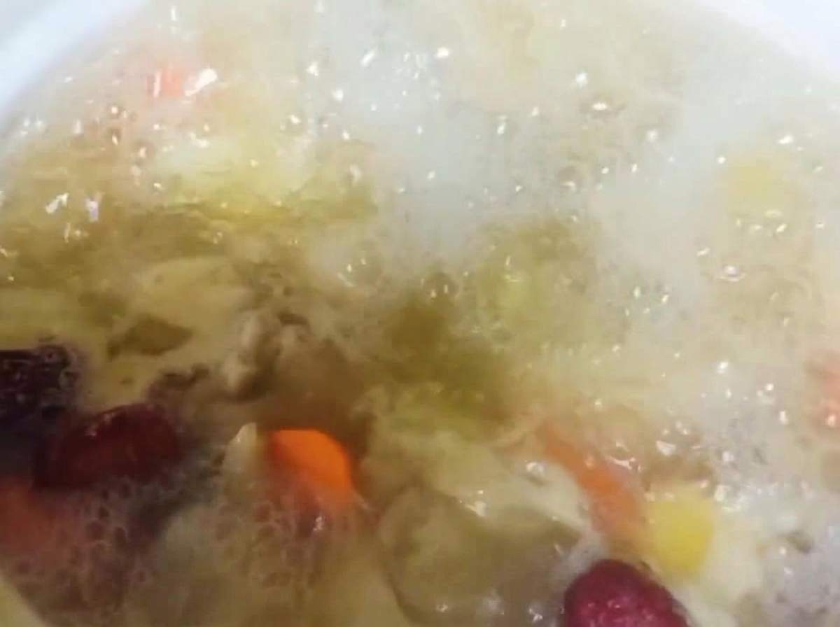 Sichuan peppercorns being added to the simmering chicken and vegetable stew.
